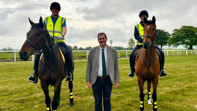 Lee Dillon centre flanked by two people on horses all stood on a race course