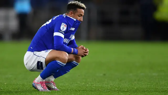 Callum Robinson of Cardiff City on his haunches with shirt pulled over his mouth in disappointment