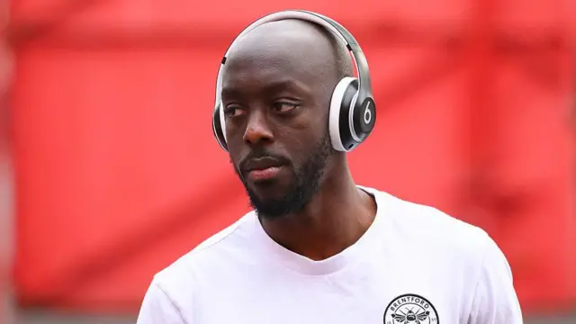 Yoane Wissa wears headphones and wears a white Brentford T-shirt