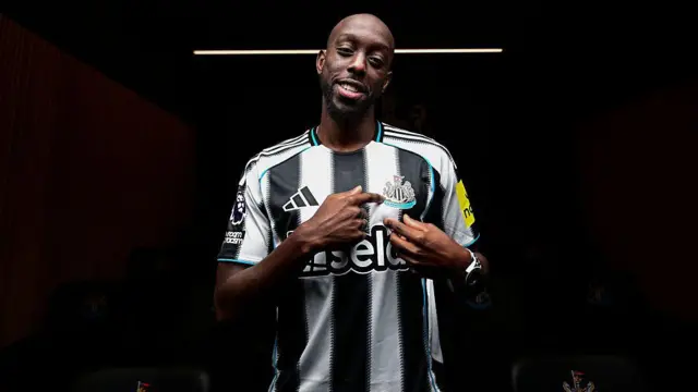Yoane Wissa poses for photographs wearing a Newcastle United home shirt