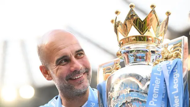 Pep Guardiola, Manager of Manchester City, poses for a photo with the Premier League title trophy following the team's victory in the Premier League match between Manchester City and West Ham United at Etihad Stadium