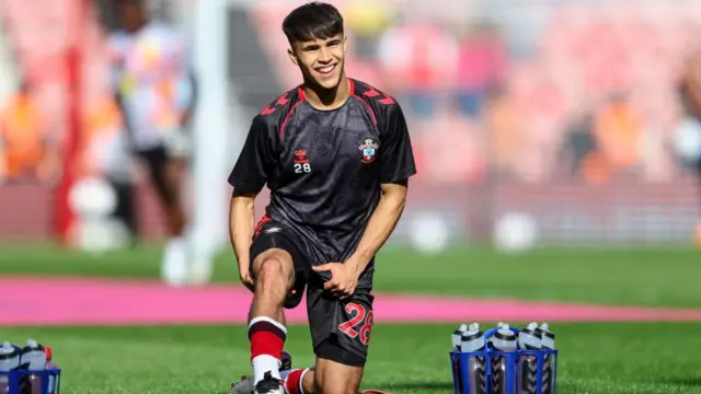 Juan Larios stretches to warm up while smiling in his Southampton top