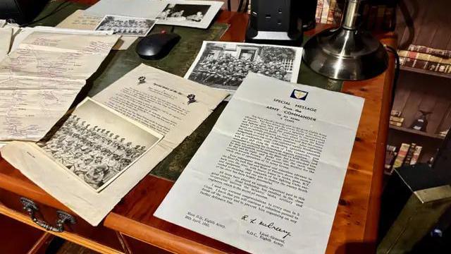 Wartime documents laid out on an old regal table.