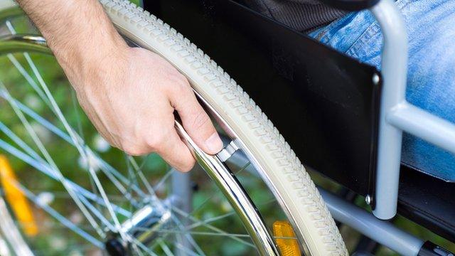 A man with his hand on the wheel of a wheelchair