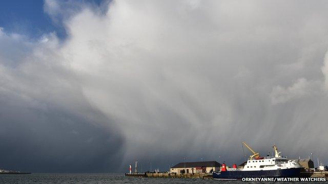 Large towering clouds with rain shafts falling, photograph taken from a harbour