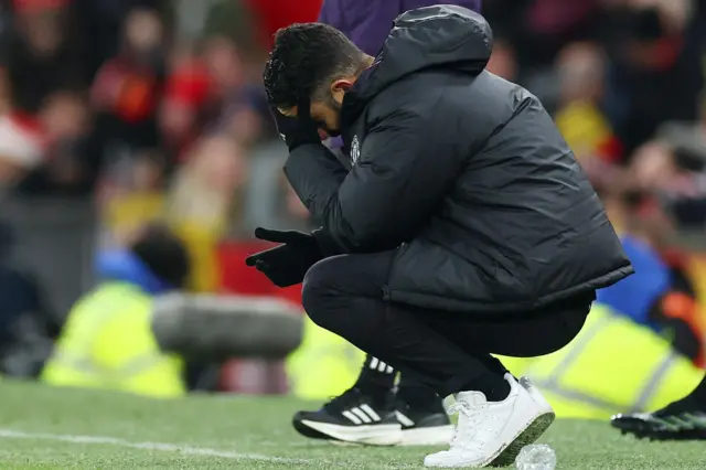 Ruben Amorim crouches on the touchline with his head in his hand