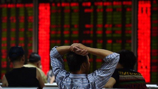 An investor looks at screens showing stock market movements in Beijing on 9 July, 2015