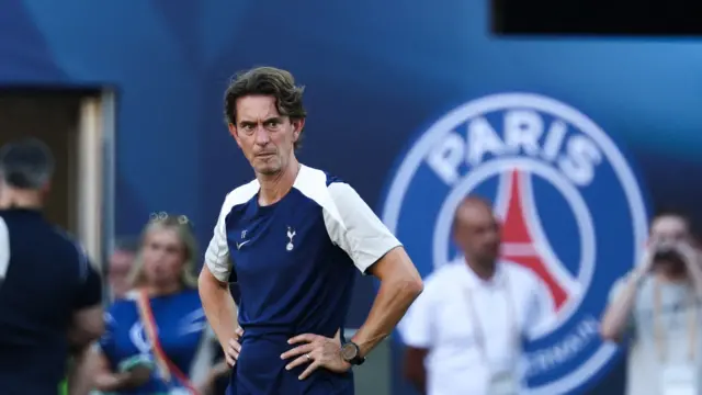 Thomas Frank looks on during a training session with Paris St-Germain badge in background