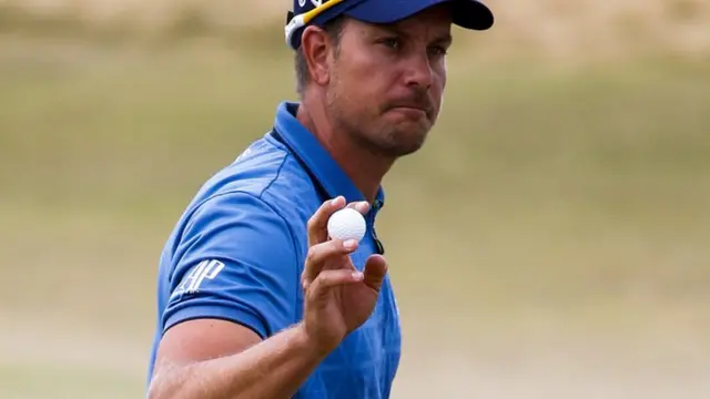 Henrik Stenson holds up his ball