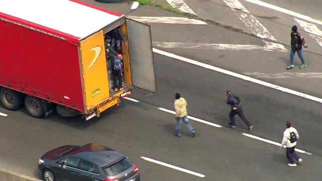 Large numbers of migrants attempting to get into cars and lorries