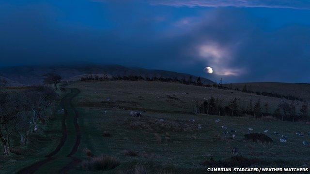 Moon slightly shrouded by clouds in a field