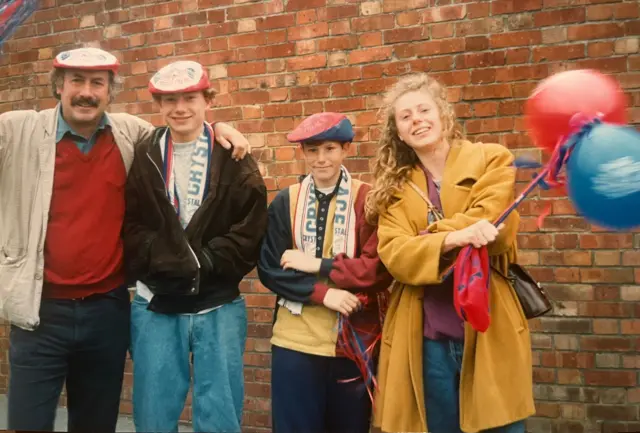A picture of a family, a dad, two boys and a mum in Palace scarves and red-and-blue berets