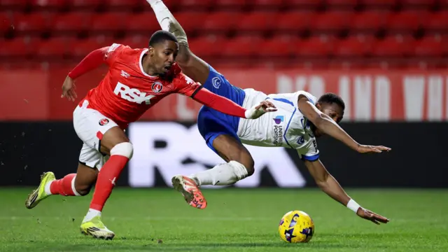Kayne Ramsay sprinting for the ball as Ebou Adam falls in the air