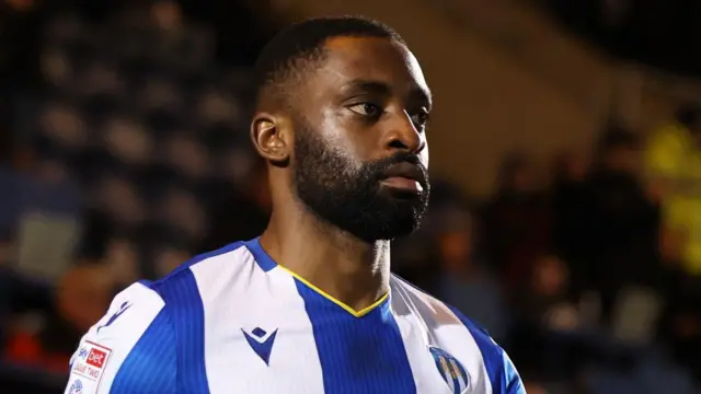 Kane Vincent-Young in a blue and white striped Colchester United home jersey before a match.