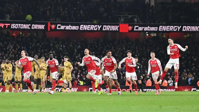 Arsenal players celebrate after winning the penalty shootout while Palace players look dejected in the background