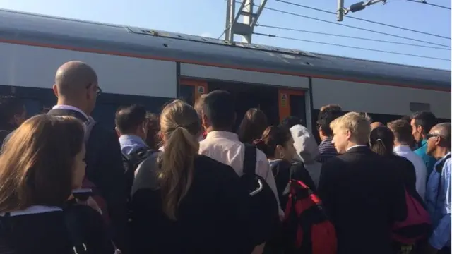 Passengers squeeze to get on the London Overground at Willesden Junction