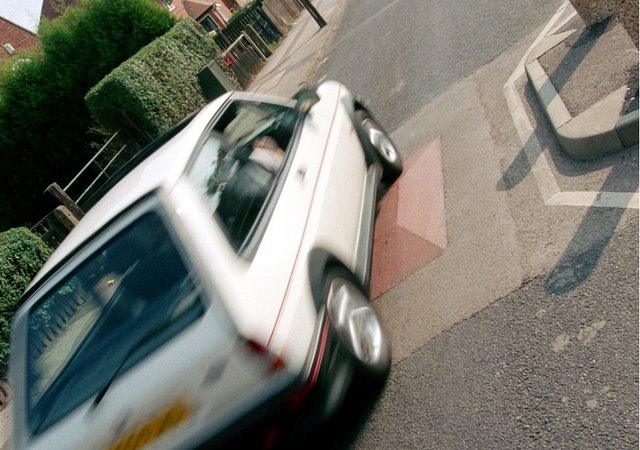 car driving over a speed bump