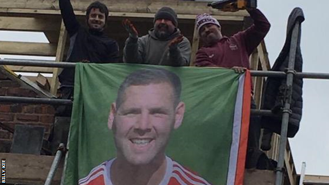 Workers on a building site near Leicester unfurl a banner of former Accrington Stanley striker Billy Kee