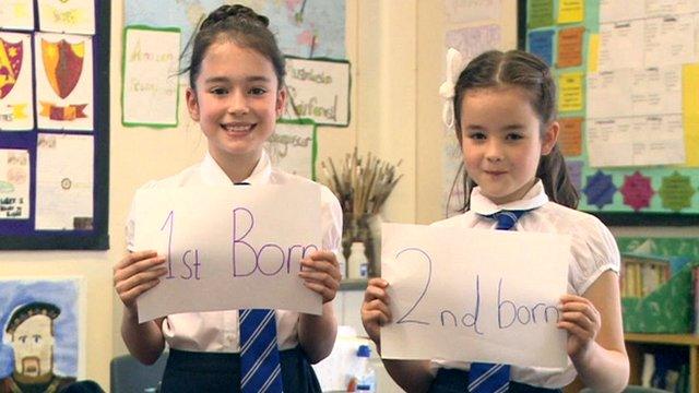 Two girls hold signs saying 1st born and 2nd born