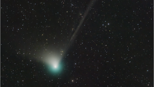 Green comet with long tail against starry black background