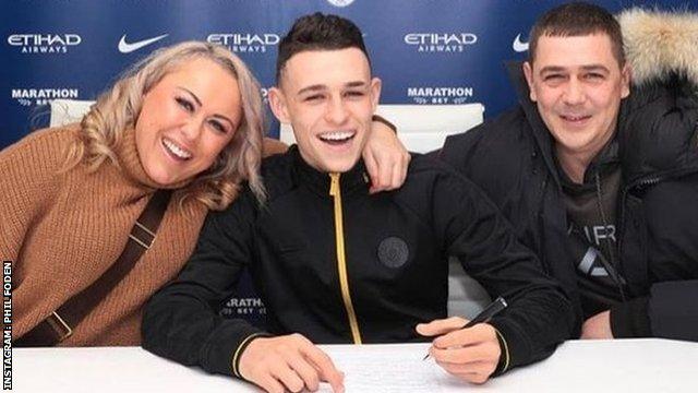 Foden is flanked by his mother Claire (left) and father Phil Snr while signing a new City contract until 2024 in December