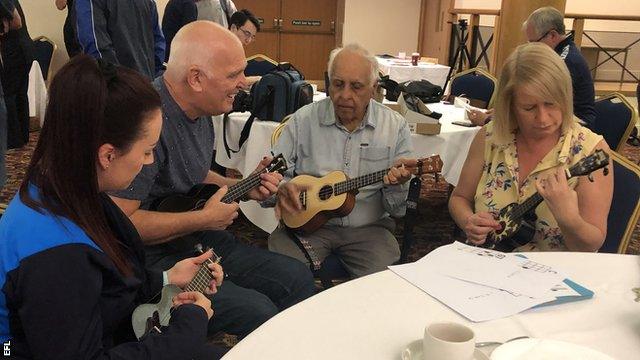 Tony Grimwood (left) teaches participants how to play the ukulele at Wigan Athletic's Extra Time Hub