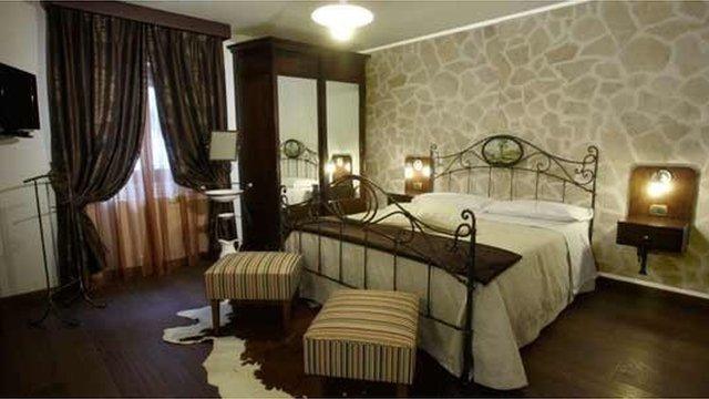 A hotel room is seen in this photo, showing a metal bed and brown, earthy tones in the decor.