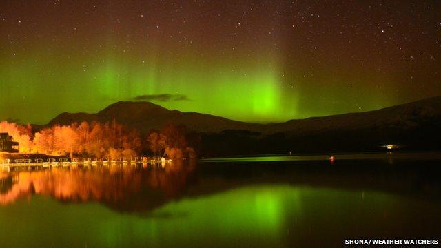 Green glow of the Northern Lights in the night sky also reflected on water