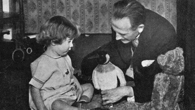 AA Milne and Christopher Robin Milne playing with a toy penguin