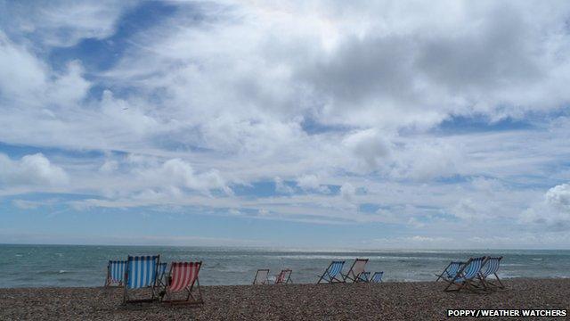 Deck chairs line a beach on a cloudy day