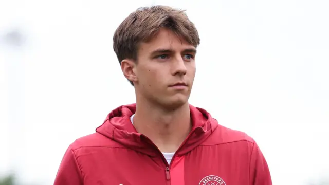 Julian Eyestone stares into the distance wearing a red Brentford training top.