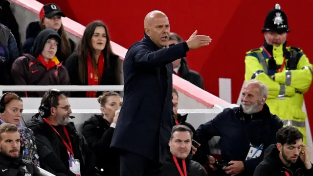 Arne Slot extends his right arm and points as he gives instructions to his Liverpool team.