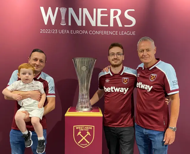 A picture of three men and a small boy stood around the Conference League trophy