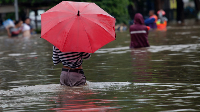 Person standing with umbrella in flooded street