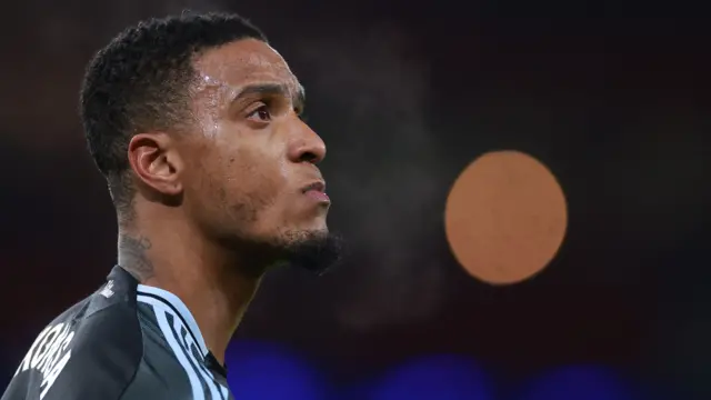 Ezri Konsa looks on wearing a black Aston Villa shirt