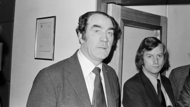 A black and white image of Joe Harvey in a suit and tie