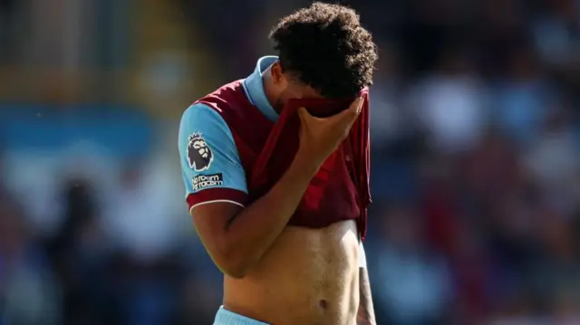 Lyle Foster holds his shirt to his face