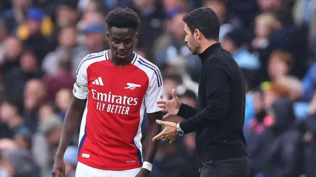 Mikel Arteta speaks to Bukayo Saka