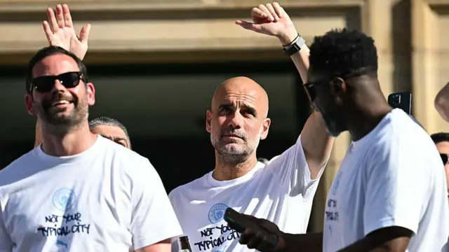Pep Guardiola waving from the open-top bus