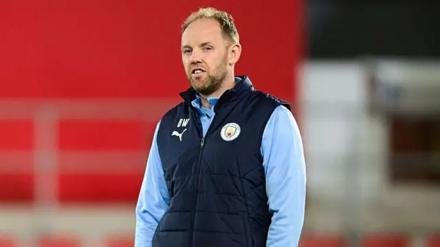 Manchester City under-21 coach Ben Wilkinson in training kit watching his team play at Rotherham