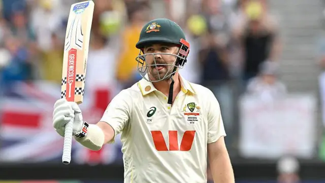 Travis Head raises his bat to celebrate his century