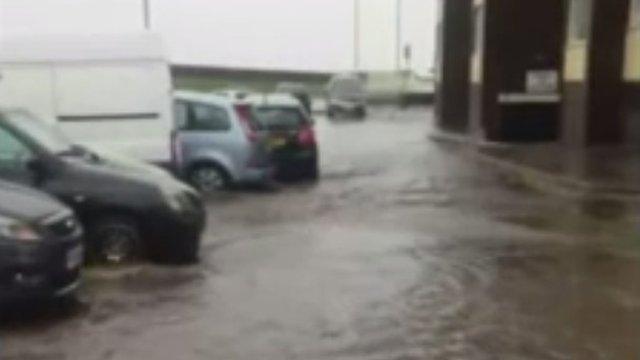 Surface flooding along a road past parked cars