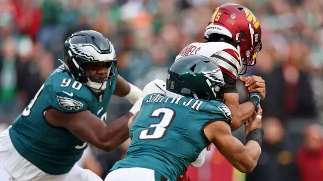 Philadelphia Eagles defensive tackle Jordan Davis and linebacker Nolan Smith Jr tackle Washington Commanders quarterback Jayden Daniels