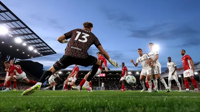 Raul Jimenez scores for Fulham against Bristol City. Players stand in the area as the ball makes its way to goal.