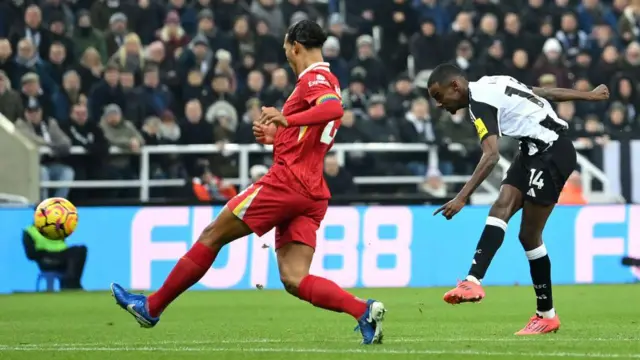 Alexander Isak of Newcastle United scores while under pressure from Liverpool's Virgil van Dijk