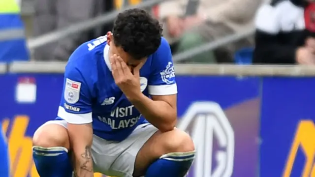A dejected Alex Robertson of Cardiff City squats and covers his face with a hand