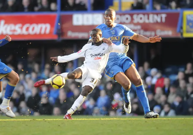 Nathan Dyer of Swansea City angles his body to shoot while holding off Sylvain Distin