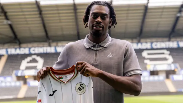 Gregory Asemokhai holds a Swansea shirt