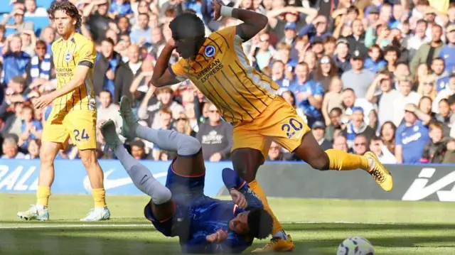 Carlos Baleba tries to avoid contact with the falling Jadon Sancho