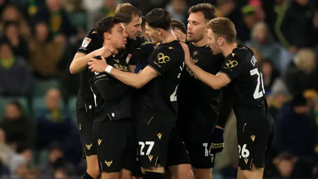 Oxford United players celebrate the 95th-minute equaliser at Norwich 